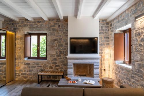 a living room with a fireplace and a tv on a stone wall at Manifest Boutique Hotel in Oítilon