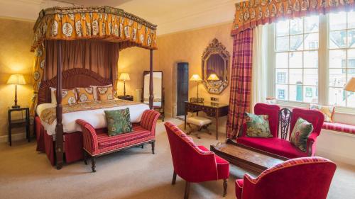 a bedroom with a canopy bed and two chairs at Luttrell Arms in Dunster