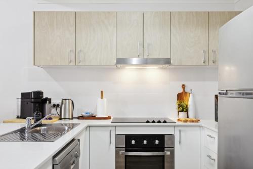a kitchen with white cabinets and a stove top oven at 3BR Oasis Townhouse in Northbridge in Perth
