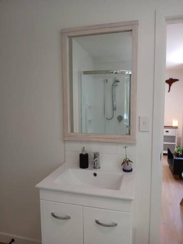 a white bathroom with a sink and a mirror at Coastal Retreat Holiday Home Rarotonga in Oneroa