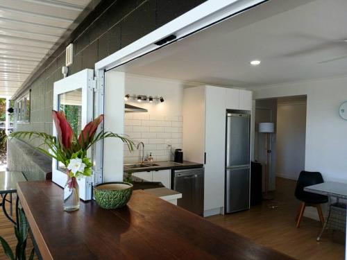 a kitchen with a table with a vase of flowers on it at Coastal Retreat Holiday Home Rarotonga in Oneroa