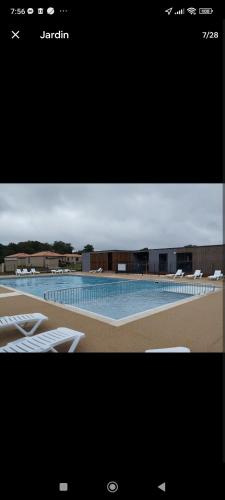 un écran de télévision montrant une piscine avec des chaises blanches dans l'établissement cottage familial piscine dans les Landes, à Saubrigues