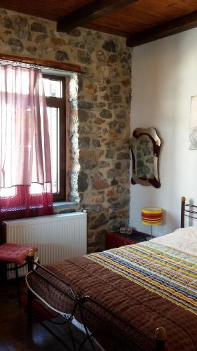 a bedroom with a bed and a stone wall at Ksenonas Chrusovitsi in Khrisovítsion