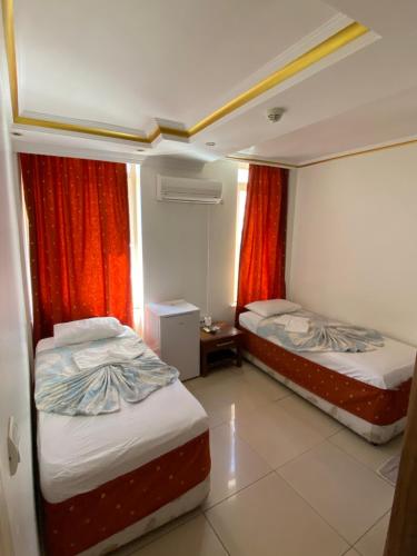 two beds in a room with red curtains at REKOR OTEl in Antalya