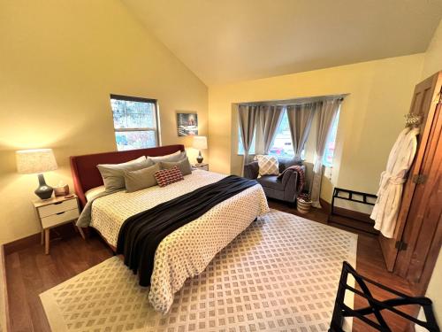 a bedroom with a bed and a chair and windows at Bell In The Woods B&B in Seward