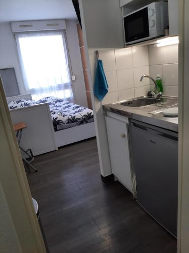 une petite cuisine avec un évier et un lit dans l'établissement Riadh, à Strasbourg