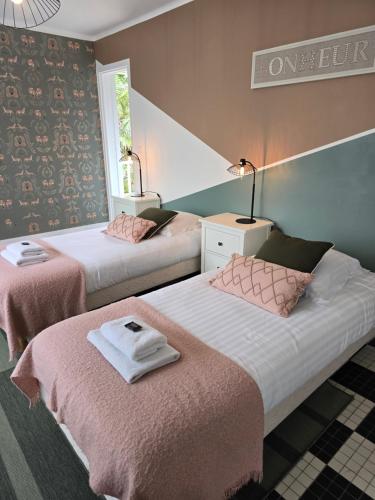 a bedroom with two beds with pink sheets and a window at Hôtel L'ideal le Mountbatten in Arromanches-les-Bains