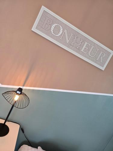 a sign on a wall above a bed with a lamp at Hôtel L'ideal le Mountbatten in Arromanches-les-Bains