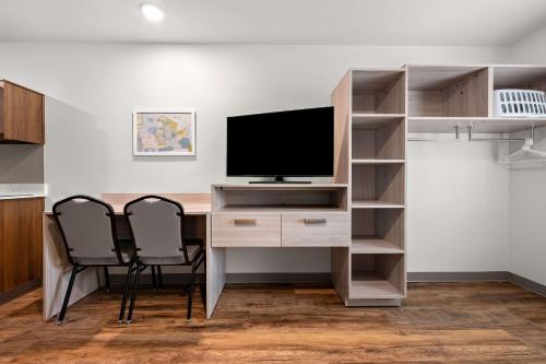 a room with a desk with a television and two chairs at WoodSpring Suites Huntsville - Research Park in Huntsville