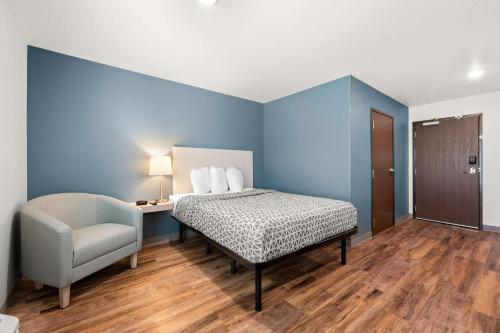 a bed and a chair in a room with blue walls at WoodSpring Suites Huntsville - Research Park in Huntsville