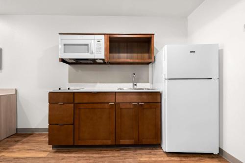 a kitchen with a white refrigerator and a microwave at WoodSpring Suites Huntsville - Research Park in Huntsville