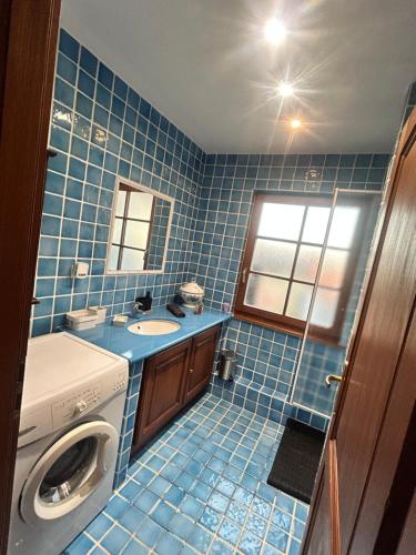 La salle de bains est pourvue de carrelage bleu et d'un lave-linge. dans l'établissement Appartement typique alsacien, à Boofzheim