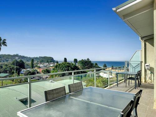 a balcony with a table and chairs and a tennis court at Unit 31 - Avoca Palms Resort in Avoca Beach