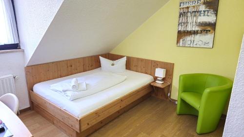 a small bedroom with a bed and a green chair at Hotel Avenue Altenfurt in Nürnberg
