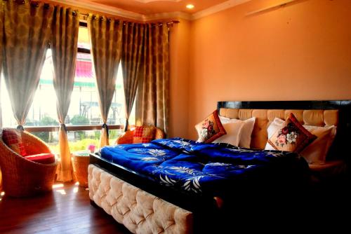 a bedroom with a bed with blue sheets and a window at Antara - A Boutique Villa By Shivaneel Hospitality, Chail in Chail