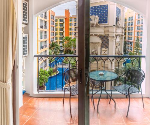 a balcony with a table and chairs and a view of a city at Venetian Resort Pattaya in Jomtien Beach