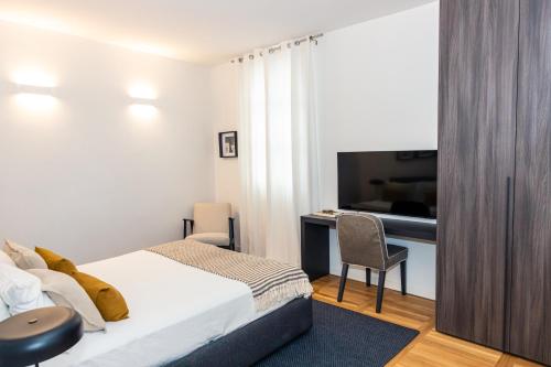 a bedroom with a bed and a desk and a television at La suite in Piazza in Erbusco