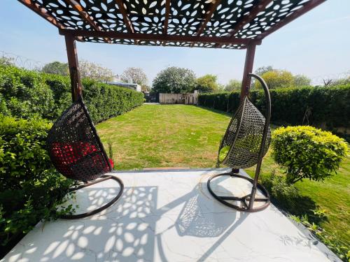 two metal chairs sitting under a pergola in a yard at Green Villa in Delhi