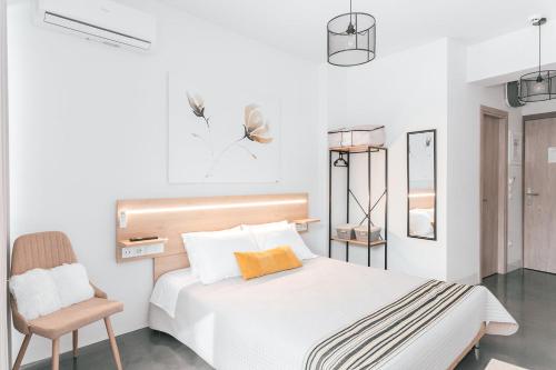 a white bedroom with a bed and a chair at MAGNOLIA SUITES in Nafpaktos