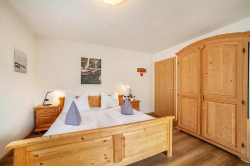 a bedroom with a wooden bed and a large wooden cabinet at Pension Klausthaler in Meltina
