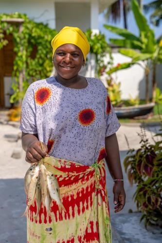 a woman is holding a bunch of fish at Coconut Mafia Island Bungalows in Utende