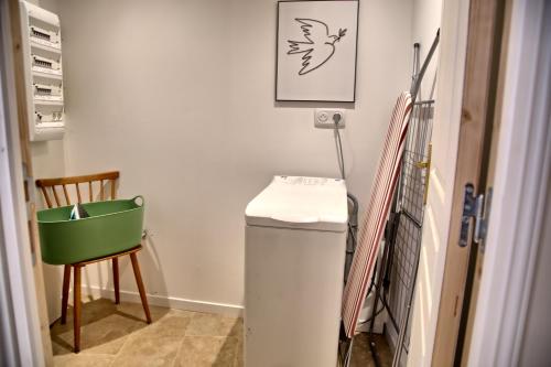 a laundry room with a trash can and a chair at Gîte le Grenier GRAY in Gray
