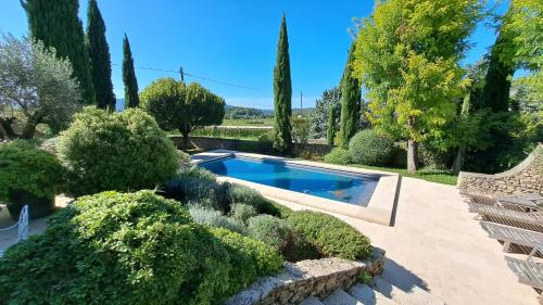 a swimming pool in a garden with trees and bushes at La Maison de Piolon in Beaumont-du-Ventoux