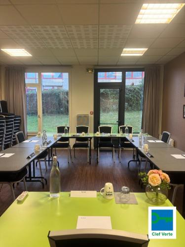 a conference room with tables and chairs and windows at Kyriad Rennes Sud - Cesson Chantepie in Chantepie
