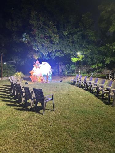 a row of chairs in a field with an elephant in the background at Serene stay in the lap of Nature in Ahmedabad
