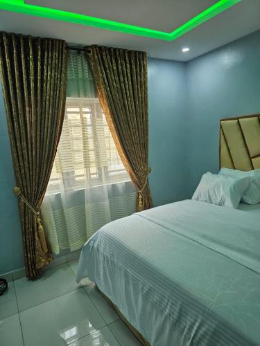 a bedroom with a bed and a window with green lights at Umbrella Properties hotels and apartments - Moniya in Ibadan