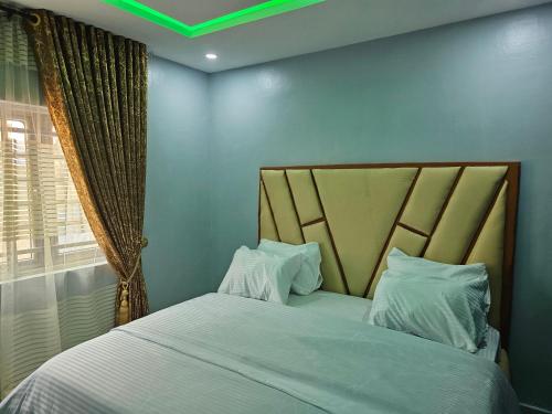 a bedroom with a bed with white sheets and a window at Umbrella Properties hotels and apartments - Moniya in Ibadan