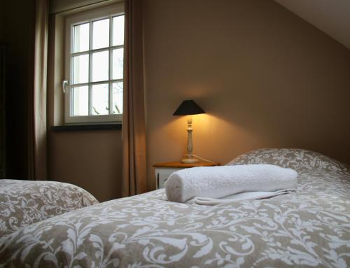 a bedroom with a bed with a white blanket and a window at Gertrude&Friends in Herbais