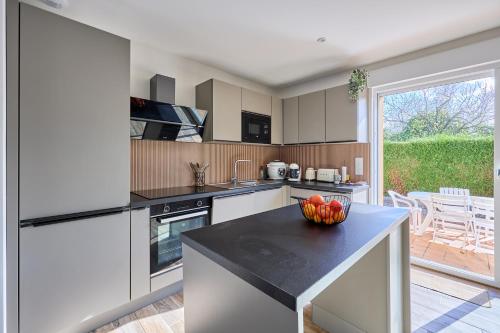 - une cuisine avec des placards blancs et un comptoir avec un bol de fruits dans l'établissement Arielle, à Bernières-sur-Mer