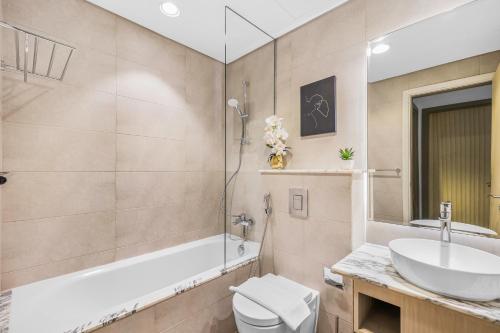 a bathroom with a sink and a tub and a toilet at 64th floor Skyline Pool with Burj Khalifa View in Paramount Hotel Midtown in Dubai