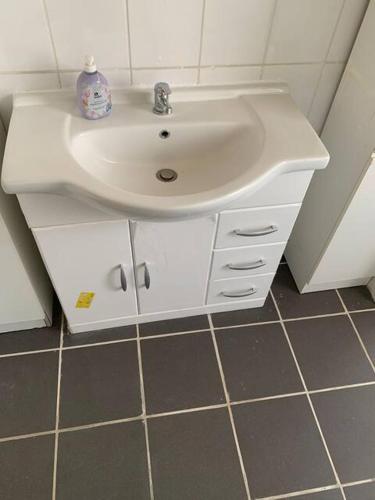 a bathroom with a white sink and a tiled floor at HD Rooms in Bremen