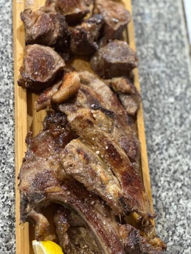 a wooden cutting board with meat on a table at VILA DISHA in Tirana