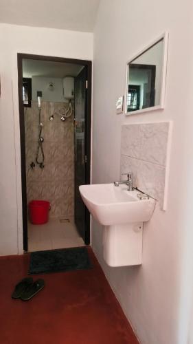 a white bathroom with a sink and a shower at THEERTHAMKARA Staycation in Nīleshwar