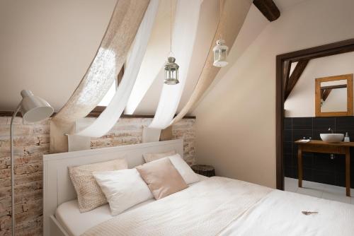 a bedroom with a white bed with white pillows at Penzion Adamův Dvůr in Masákova Lhota