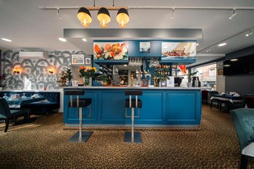a restaurant with a blue bar with tables and chairs at BRIT HOTEL PRIVILEGE LISIEUX - La Villa des Arts in Lisieux