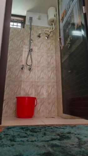 a shower with a red bucket in a bathroom at THEERTHAMKARA Staycation in Nīleshwar