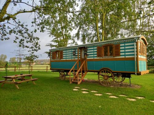 un wagon de train bleu garé dans un parc avec une table de pique-nique dans l'établissement Roulotte de charme, à Villers-sur-Authie
