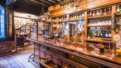 a bar with a long counter with alcohol bottles at Luttrell Arms in Dunster