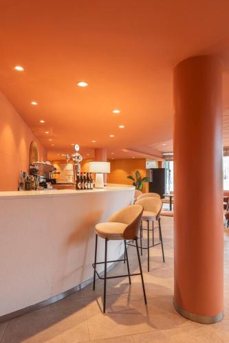 a lobby with an orange ceiling with stools and a counter at Acta Sant Just in Sant Just Desvern