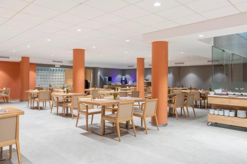 a restaurant with wooden tables and chairs and orange pillars at Acta Sant Just in Sant Just Desvern