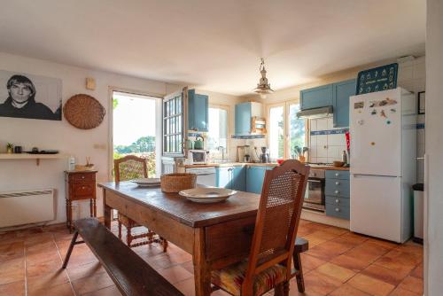 une cuisine avec des placards bleus et une table en bois avec des chaises dans l'établissement L’Écrin de Bégarosse - Maison à Belle-Île-en-Mer, au Palais