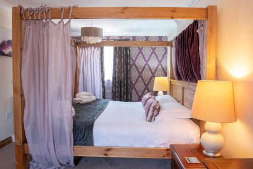 a bedroom with a canopy bed with white sheets at Wild Oats Lodge 6, Yellowtop Country Park in York