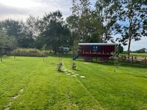 a train car sitting in a field of grass at Roulotte, pleine de charme in Villers-sur-Authie