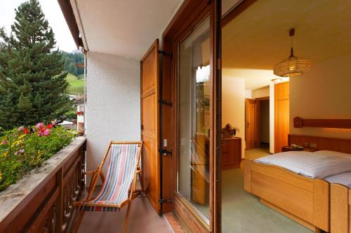 a room with a balcony with a bed and a window at Hotel Genziana in Arabba