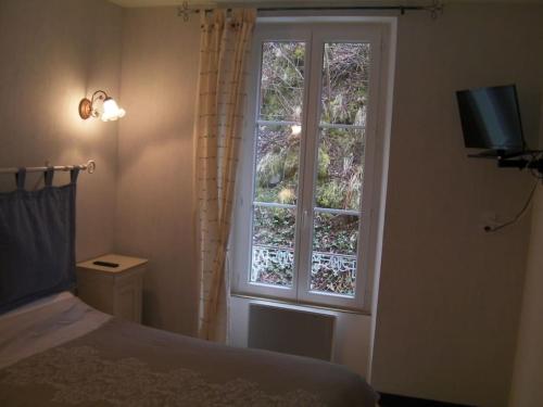 a bedroom with a window and a bed and a television at Appartement à la montagne in Le Mont-Dore