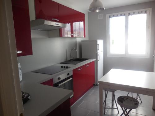 une cuisine avec des armoires rouges et un comptoir blanc dans l'établissement Appartement agréable, à Grenoble